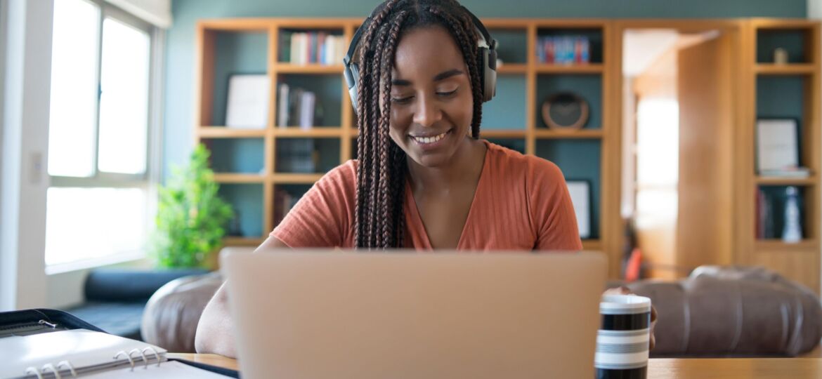 portrait-woman-video-call-with-laptop-headphones-while-working-from-home-concept-min