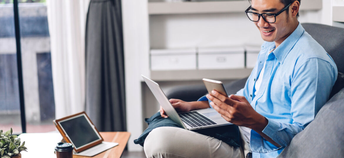 Young smiling asian man relaxing using laptop computer working a