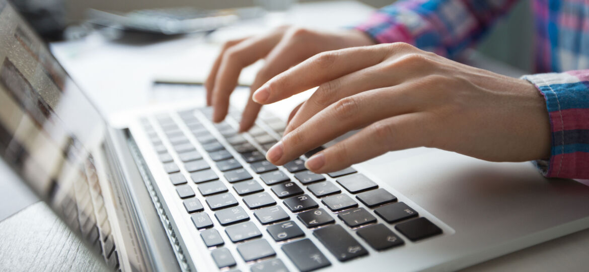 Cropped View of Hands Typing on Laptop