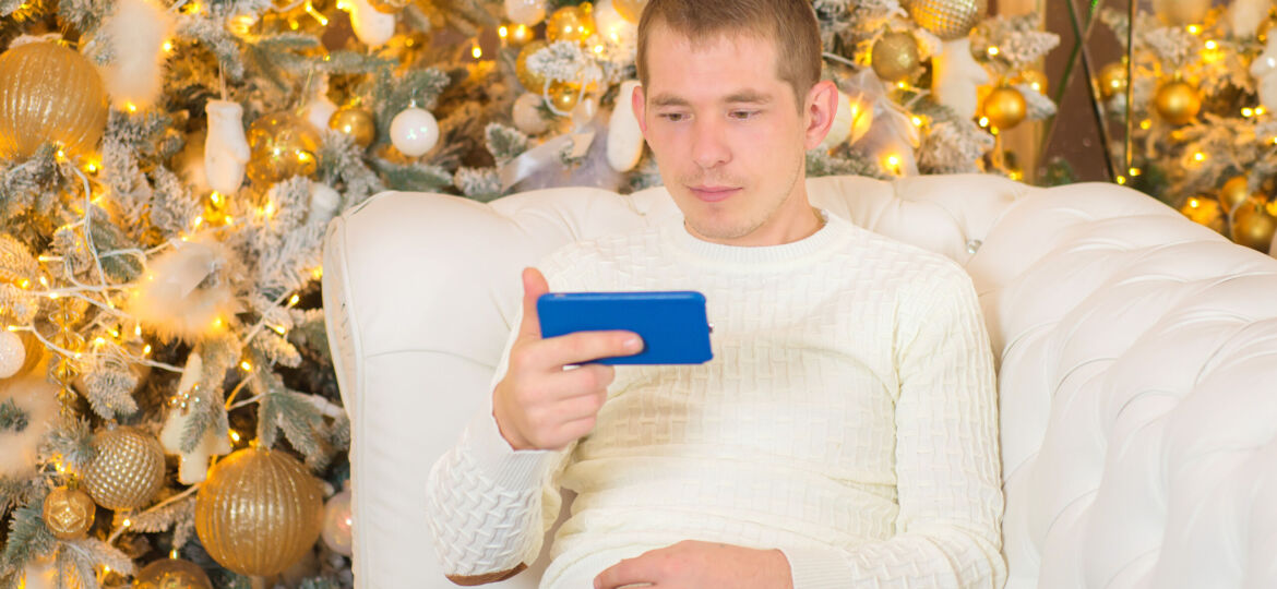 young-man-with-phone-near-christmas-tree-christmas