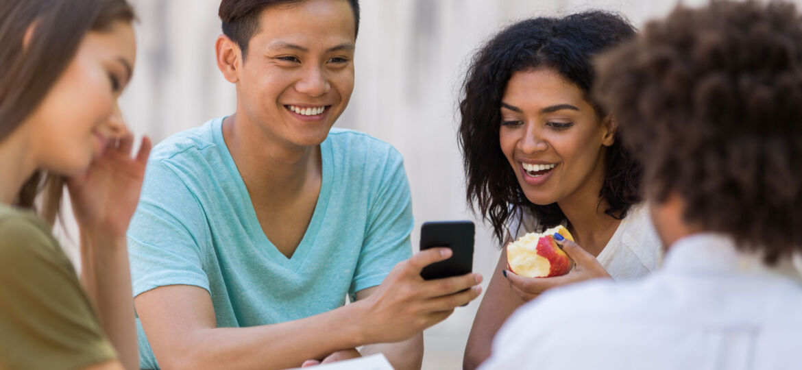 Cheerful young multiethnic group of friends students talking using phone