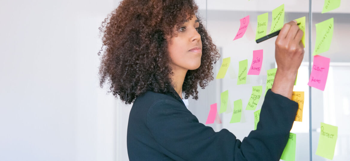 African American businesswoman writing on sticker with marker