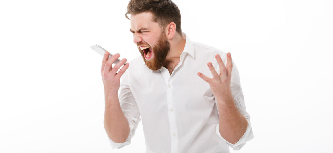 Angry bearded man in business clothes screaming at smartphone
