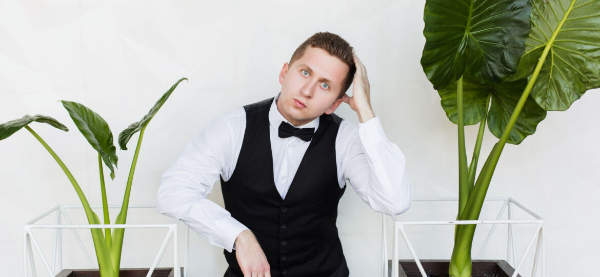 Perspective young man, future generation of businessman stand near green plant on white background.