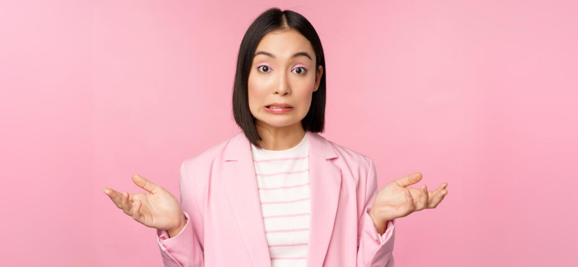 portrait-confused-asian-businesswoman-shrugging-shoulders-looking-clueless-puzzled-dont-know-cant-say-standing-pink-background-office-suit