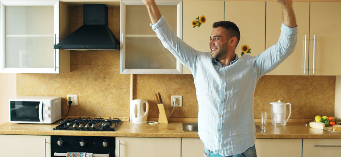 Handsome young funny man dancing in kitchen at home in the morning and have fun on holidays