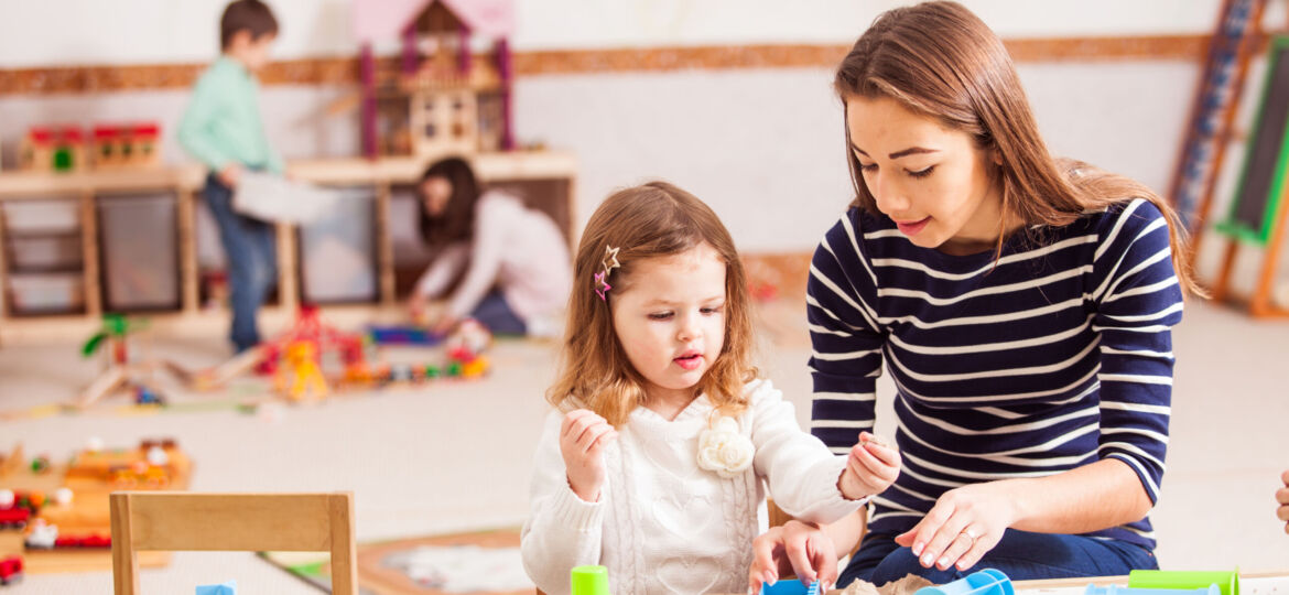 the teacher is teaching the girl to Make sand shapes