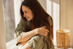Woman smiling, hugging herself, staying positive