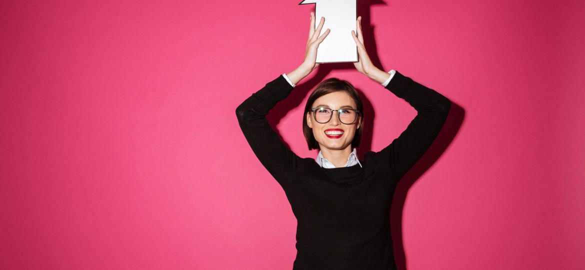 Portrait of a happy young businesswoman holding paper arrow sign