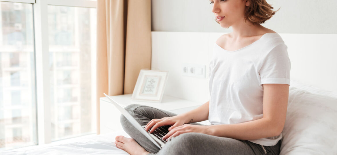Young beautiful woman sitting indoors using laptop