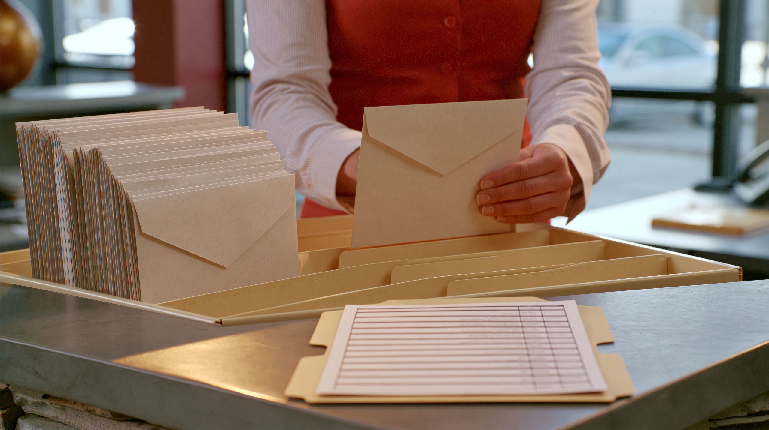 Person sorting printed envelopes at a desk, representing envelope manufacturing and printing jobs with SupremeX in Mississauga