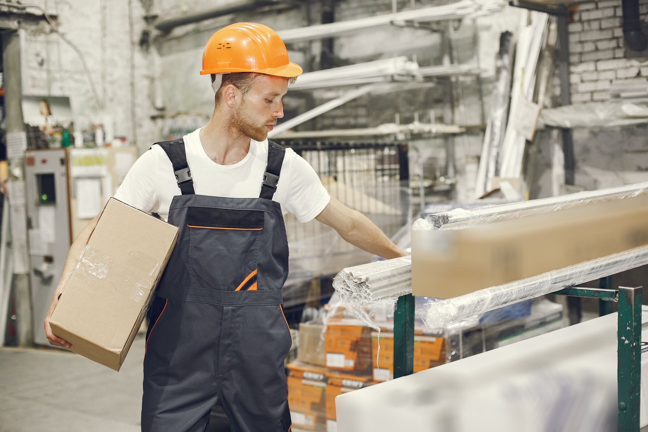 Young technician in an orange hard hat working in a factory, representing envelope machine adjustor and general labour printing jobs at the SupremeX job fair at Job Skills Mississauga